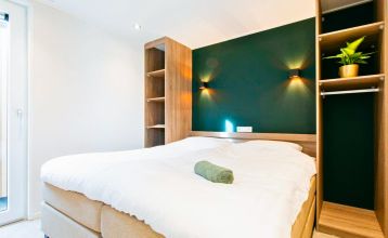 Duinrell is een modern huis van twee verdiepingen met een metalen dak, grote ramen en een houten buitenkant in de buurt van sportinfrastructuur. Geniet van een overdekte patio met buiteneten en meubilair op een verzorgd gazon omringd door bomen onder de b