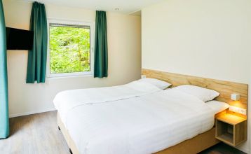 Duinrell is een modern huis van twee verdiepingen met een metalen dak, grote ramen en een houten buitenkant in de buurt van sportinfrastructuur. Geniet van een overdekte patio met buiteneten en meubilair op een verzorgd gazon omringd door bomen onder de b