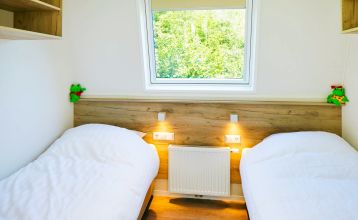 Duinrell is een modern huis van twee verdiepingen met een metalen dak, grote ramen en een houten buitenkant in de buurt van sportinfrastructuur. Geniet van een overdekte patio met buiteneten en meubilair op een verzorgd gazon omringd door bomen onder de b