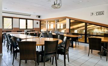 Fun4You sportpark biedt een lichte vergaderruimte met houten tafels, zwarte geweven stoelen, grote ramen en een Bundes Liga-bord - ideaal voor teambuilding na activiteiten op het nabijgelegen sportveld. Er is een plafondprojector beschikbaar boven de tege