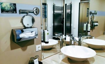 Hotel Stadt Mühlhausen*** is een groot, modern, grijs-wit gebouw met ronde ramen, een bord boven de ingang, bomen in de buurt, een bewolkte hemel en een eigen fitnessruimte voor het comfort van de gasten.