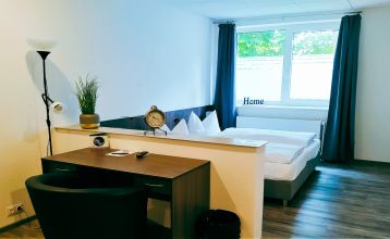 Hotel Stadt Mühlhausen*** is een groot, modern, grijs-wit gebouw met ronde ramen, een bord boven de ingang, bomen in de buurt, een bewolkte hemel en een eigen fitnessruimte voor het comfort van de gasten.