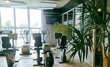 Hotel Stadt Mühlhausen*** is een groot, modern, grijs-wit gebouw met ronde ramen, een bord boven de ingang, bomen in de buurt, een bewolkte hemel en een eigen fitnessruimte voor het comfort van de gasten.