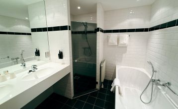 Hotel De Beyaerd biedt een ruim, modern restaurant met grote glazen ramen, lichthouten tafels, grijze en mosterdkleurige stoelen, hangende potplanten en uitzicht op bomen - ideaal voor teambuildingsactiviteiten.