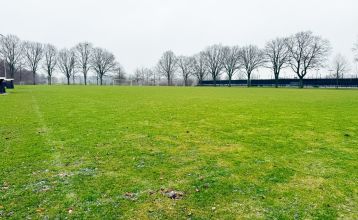 Marveld Recreatie heeft een historisch bakstenen gebouw met een toren, grote ramen en een rood dak in Groenlo. Omgeven door tuinen en bungalows staat een oud kanon op het pad in dit charmante vakantiepark.