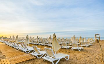 Het Side Moon Palace is een modern hotel met meerdere verdiepingen en balkons vanwaar gasten kunnen genieten van het uitzicht op een ruim buitenzwembad, omringd door rijen witte ligstoelen en gesloten parasols.