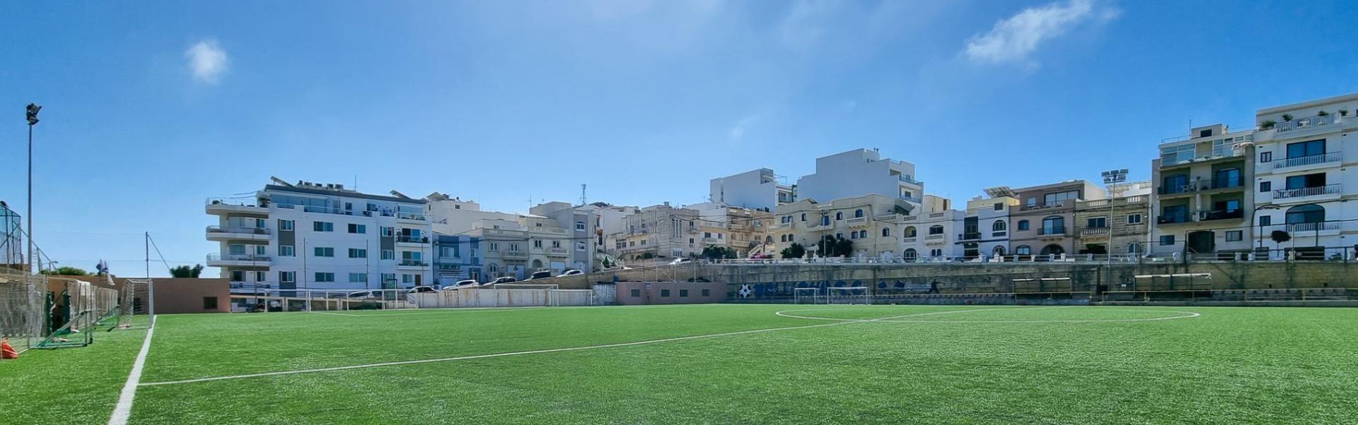 Moderne kunstgressbane i Mellieħa, omgitt av middelhavsarkitektur &ndash; ideell for intensive trenings&oslash;kter under Maltas sol.