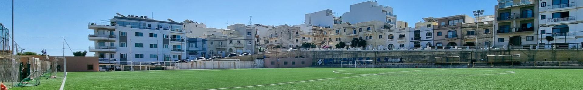 Moderne kunstgressbane i Mellieħa, omgitt av middelhavsarkitektur &ndash; ideell for intensive trenings&oslash;kter under Maltas sol.