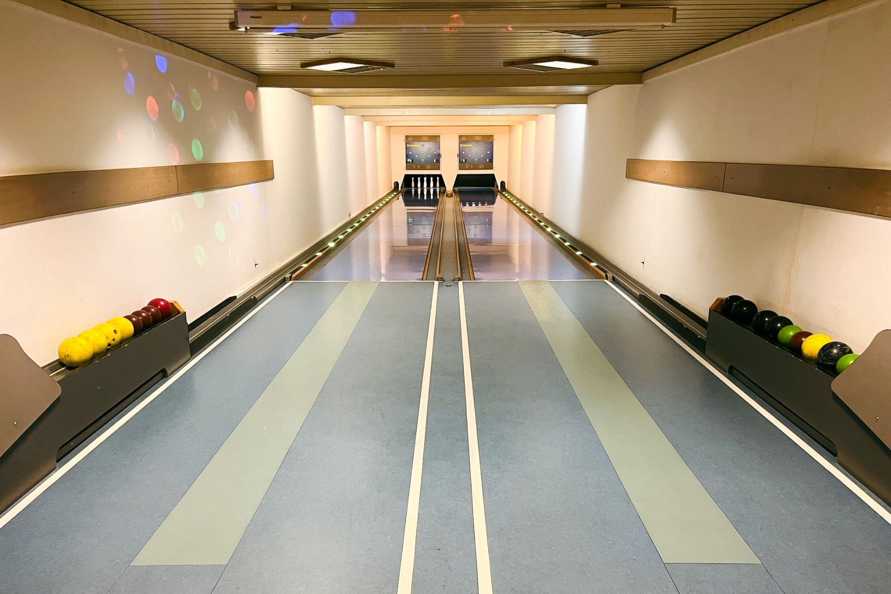 Das Egger Stüberl bietet eine hell beleuchtete Kegelbahn mit zwei Bahnen, bunten Kugeln auf seitlichen Ständern, Kegeln am Ende jeder Bahn und bunten Lichtern an der Wand - ein idealer Ort, um nach dem Besuch der Fußballplätze zu entspannen.
