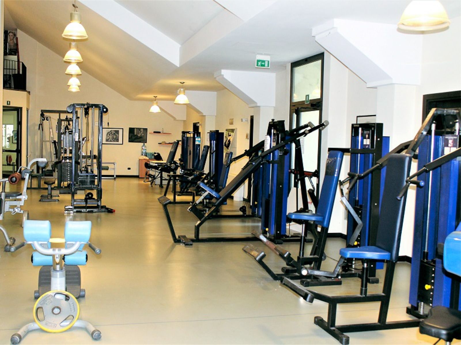 Der gut beleuchtete Fitnessraum der Appartements Residence Eden*** bietet eine Reihe von Trainingsgeräten wie Hanteln, stationäre Fahrräder und Bänke, die alle in einem großzügigen Bereich angeordnet sind - ideal für preisbewusste Mannschaften.