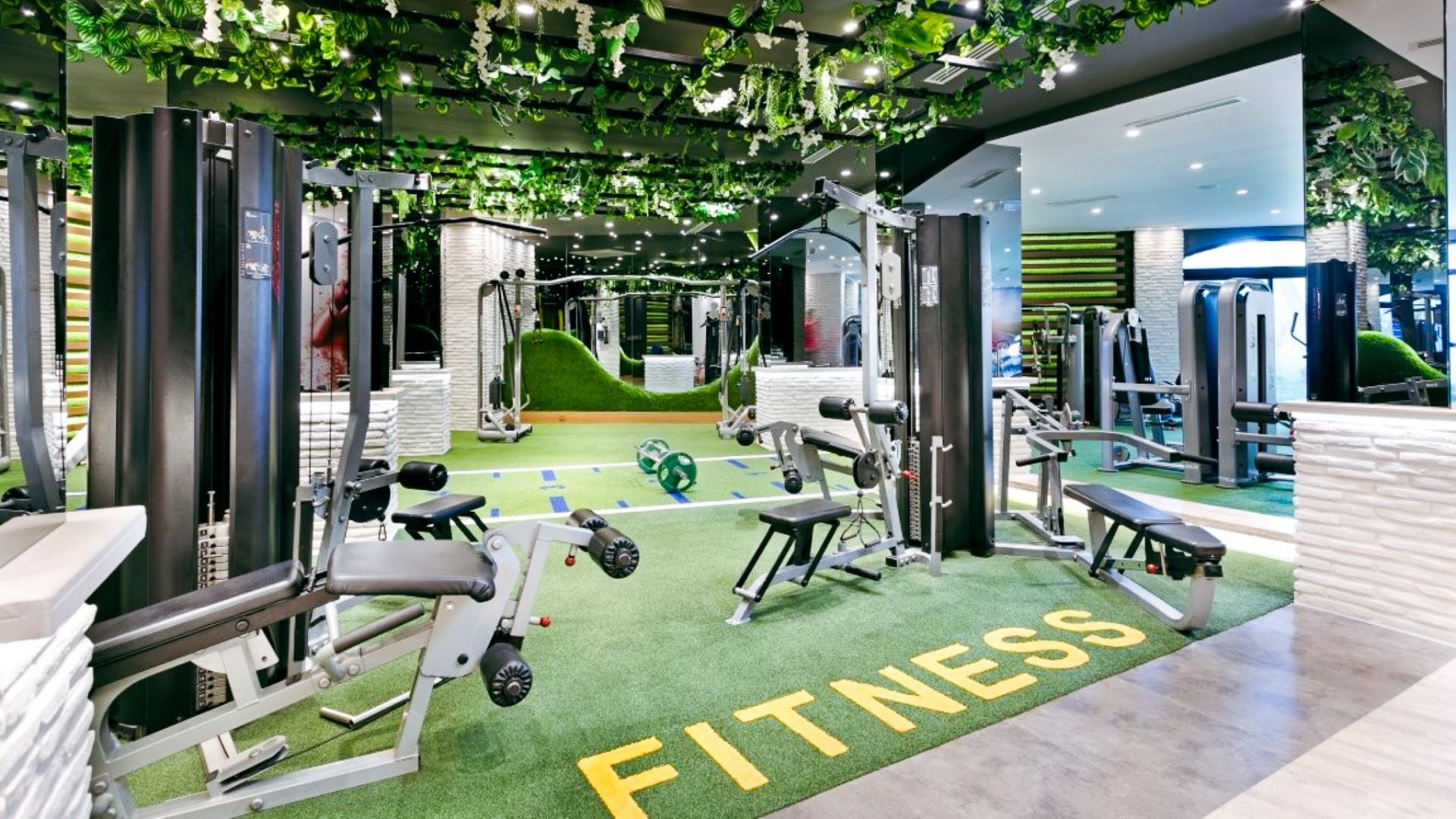 Det moderne treningsstudioet på Limak Arcadia Hotel har treningsutstyr og benker på en grønn gressplen merket FITNESS, supplert med speil og hengende grønne planter - et friskt og levende rom som er perfekt for fotballtreningsleiren i Tyrkia.