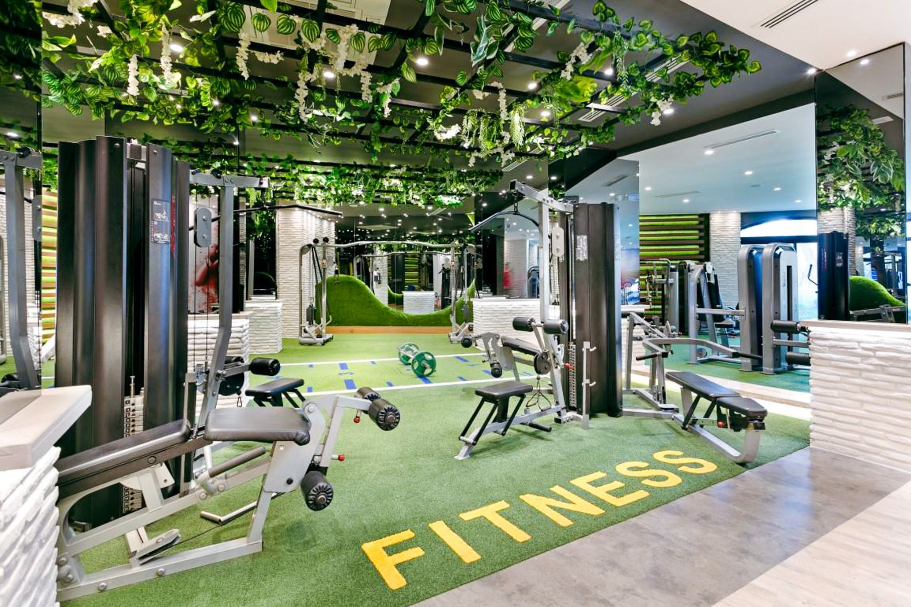Limak Arcadia Hotel tilbyr et moderne treningsstudio med en grønn gressplen merket FITNESS, flere apparater, speil, grønn takdekor og sterk belysning - ideelt for treningsøkter eller fotballtreningsleirer i Tyrkia på et førsteklasses hotell.