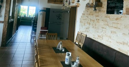 Luftaufnahme des Breitenberger Hofs*** mit Sonnenkollektoren und einem Wellnessbereich auf dem Dach, umgeben von geparkten Autos und H&auml;usern in einer kleinen, h&uuml;geligen Stadt bei Passau. Auf dem Boden sind Schneeflecken zu sehen.