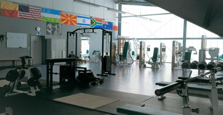 Zwei weiße Lieferwagen mit dem Schriftzug "The Wolfpack" parken vor einem Wohngebäude mit der Aufschrift Sportcampus Schlotheim, das für seine geräumigen Zimmer und ein modernes Fitnessstudio bekannt ist. Blauer Himmel und Bäume rahmen die Szene ein.