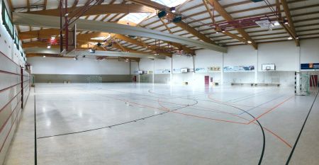 Zwei weiße Lieferwagen mit dem Schriftzug "The Wolfpack" parken vor einem Wohngebäude mit der Aufschrift Sportcampus Schlotheim, das für seine geräumigen Zimmer und ein modernes Fitnessstudio bekannt ist. Blauer Himmel und Bäume rahmen die Szene ein.