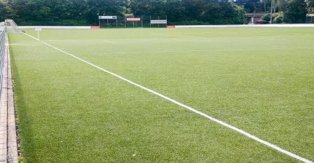 Ein verschn&ouml;rkelter schwarzer Metallbogen mit einer h&auml;ngenden Laterne steht am Eingang des Parks in der N&auml;he eines wei&szlig;en Geb&auml;udes mit rotem Ziegeldach und B&auml;umen - ideal f&uuml;r Besucher, die zum G&auml;stehaus Northeim wollen oder auf der Suche nach nahe gelegen