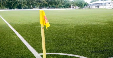 Ein verschn&ouml;rkelter schwarzer Metallbogen mit einer h&auml;ngenden Laterne steht am Eingang des Parks in der N&auml;he eines wei&szlig;en Geb&auml;udes mit rotem Ziegeldach und B&auml;umen - ideal f&uuml;r Besucher, die zum G&auml;stehaus Northeim wollen oder auf der Suche nach nahe gelegen