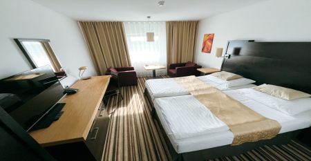 Luftaufnahme des Parkhotels mit Sonnenkollektoren, Au&szlig;enpool, Tennispl&auml;tzen, Fitnessstudio und gro&szlig;em Parkplatz inmitten von B&auml;umen nahe dem Stadtzentrum von Pilsen an einem sonnigen Tag.