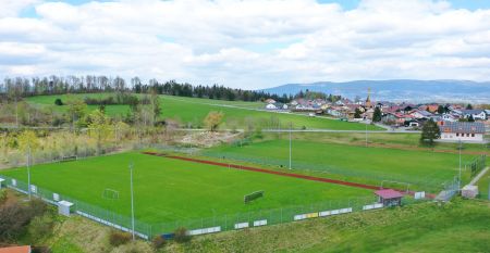 Luftaufnahme des Breitenberger Hofs*** mit Sonnenkollektoren und einem Wellnessbereich auf dem Dach, umgeben von geparkten Autos und H&auml;usern in einer kleinen, h&uuml;geligen Stadt bei Passau. Auf dem Boden sind Schneeflecken zu sehen.