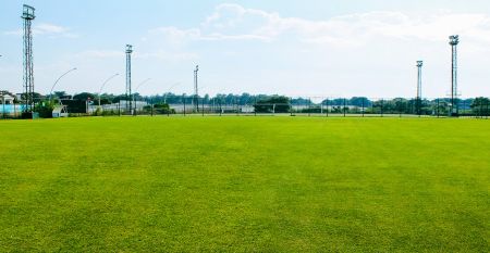 Luftfoto av Limak Arcadia Hotel med bassenger, hager, idrettsbaner og strandhytter - ideelt for fotballtreningsleiren i Tyrkia - omgitt av palmer og fjell under en klar himmel.