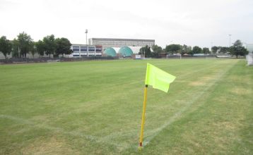 Moderne zweistöckige Appartements Residence Eden*** mit Balkonen und braunen Dächern, eingebettet in grüne Rasenflächen und Sträucher mit gepflasterten Gehwegen unter blauem Himmel - ideal für preisbewusste Mannschaften, die Komfort suchen.