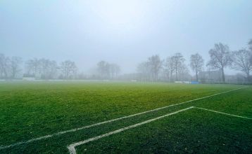 Das Sporthotel Bruurs ist ein modernes zweistöckiges Gebäude mit gelben Dächern und Wellness-Schildern, umgeben von grünen Hecken und Bäumen in Baarle-Nassau unter einem teilweise bewölkten Himmel - ideal für ein Trainingslager.