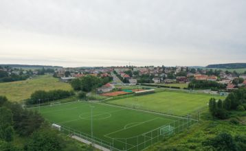 Luftaufnahme des Parkhotels mit Sonnenkollektoren, Außenpool, Tennisplätzen, Fitnessstudio und großem Parkplatz inmitten von Bäumen nahe dem Stadtzentrum von Pilsen an einem sonnigen Tag.