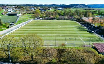 Hotel Empfinger Hof, med rødt tegltak og kvistevinduer, ønsker gjester velkommen til Fußballtrainingslager. Et "Hotel Restaurant"-skilt kroner bygningen, med trær og en asfaltert inngang som tilbyr gute Verpflegung og solrik varme.
