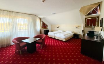 Hotel Empfinger Hof, med rødt tegltak og kvistevinduer, ønsker gjester velkommen til Fußballtrainingslager. Et "Hotel Restaurant"-skilt kroner bygningen, med trær og en asfaltert inngang som tilbyr gute Verpflegung og solrik varme.