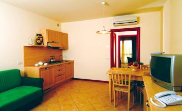 Moderne zweistöckige Appartements Residence Eden*** mit Balkonen und braunen Dächern, eingebettet in grüne Rasenflächen und Sträucher mit gepflasterten Gehwegen unter blauem Himmel - ideal für preisbewusste Mannschaften, die Komfort suchen.