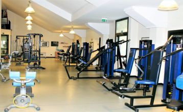 Moderne zweistöckige Appartements Residence Eden*** mit Balkonen und braunen Dächern, eingebettet in grüne Rasenflächen und Sträucher mit gepflasterten Gehwegen unter blauem Himmel - ideal für preisbewusste Mannschaften, die Komfort suchen.