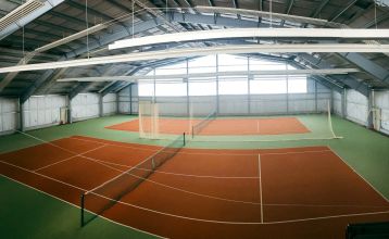 Zwei weiße Lieferwagen mit dem Schriftzug "The Wolfpack" parken vor einem Wohngebäude mit der Aufschrift Sportcampus Schlotheim, das für seine geräumigen Zimmer und ein modernes Fitnessstudio bekannt ist. Blauer Himmel und Bäume rahmen die Szene ein.