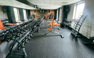 Luftaufnahme des Parkhotels mit Sonnenkollektoren, Außenpool, Tennisplätzen, Fitnessstudio und großem Parkplatz inmitten von Bäumen nahe dem Stadtzentrum von Pilsen an einem sonnigen Tag.