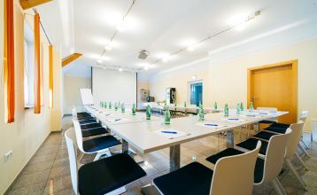 Hotell- og restaurant Schachenwald er en strålende gul, toetasjes bygning med rødt takstein under blå himmel – ideelt for treningsleirer – med potteplanter ved inngangen og biler parkert på den brosteinsbelagte oppkjørselen.