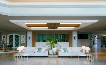 Hotel SH Villa Gadea* er et feriested ved kysten med utsikt over havet, en stor hvit bygning, et svømmebasseng, palmer og grønne plener – ideelt for fotballag under treningsleiren i Altea under en knallblå himmel.