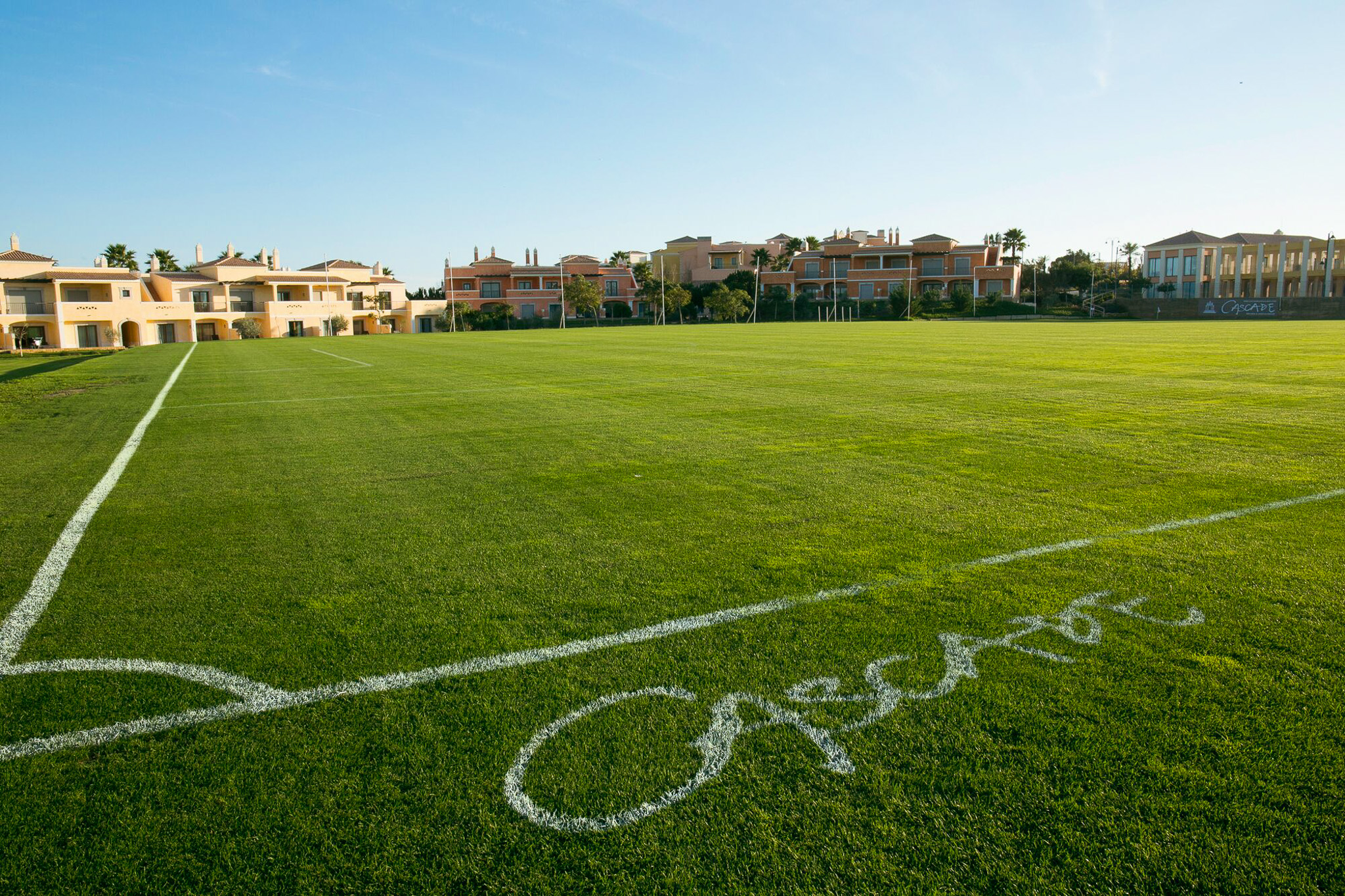 Fu&szlig;ballplatz in der Algarve mit direkter Hotelanbindung und Palmen im Hintergrund.