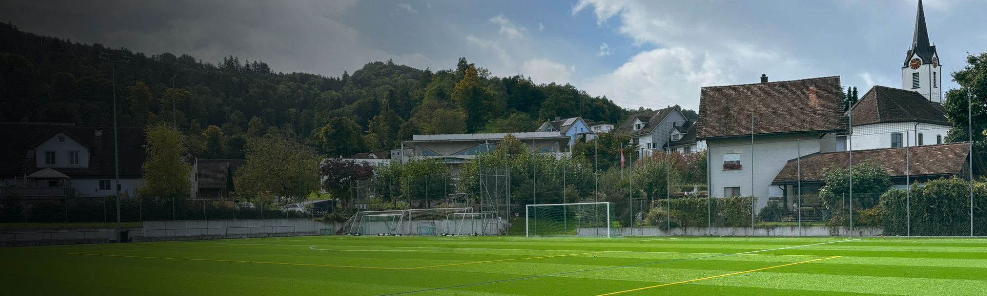 Panoramaaufnahme des Fu&szlig;ballplatzes in Mellieħa mit angrenzenden Wohnh&auml;usern &ndash; perfekte Trainingsbedingungen in einer sonnigen K&uuml;stenstadt.
