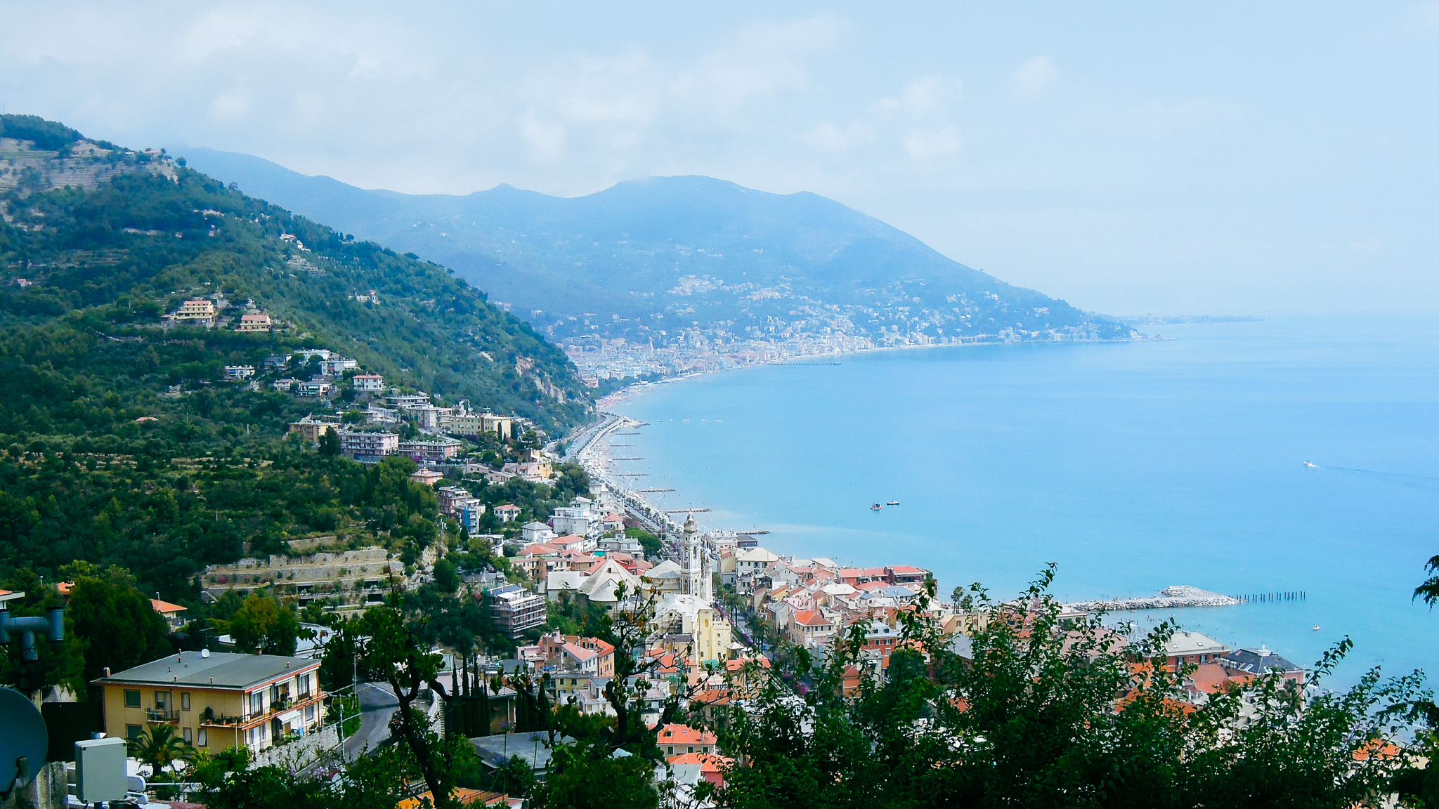 Luftaufnahme der Italienischen Riviera mit Blick auf die K&uuml;ste, die blau schimmernde Bucht und die in die gr&uuml;nen Bergh&auml;nge eingebettete Stadt.
