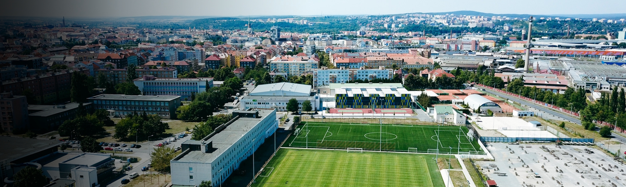 Fu&szlig;balltrainingsanlage in einer Stadtlandschaft, mit mehreren Fu&szlig;ballfeldern und modernen Einrichtungen.