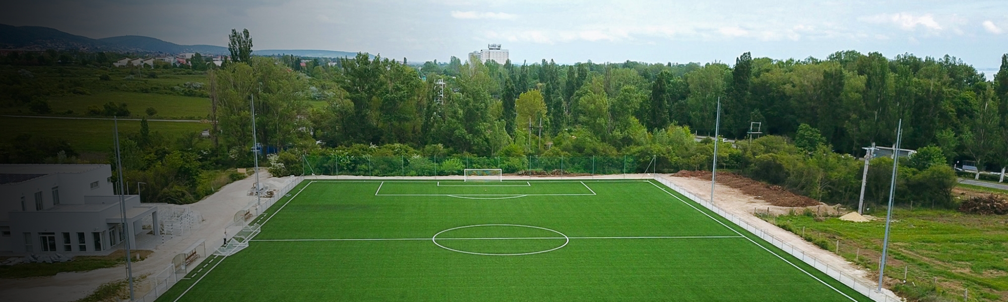 Panoramaaufnahme eines Fu&szlig;ballfeldes mit klaren Linien, in einer l&auml;ndlichen Gegend..