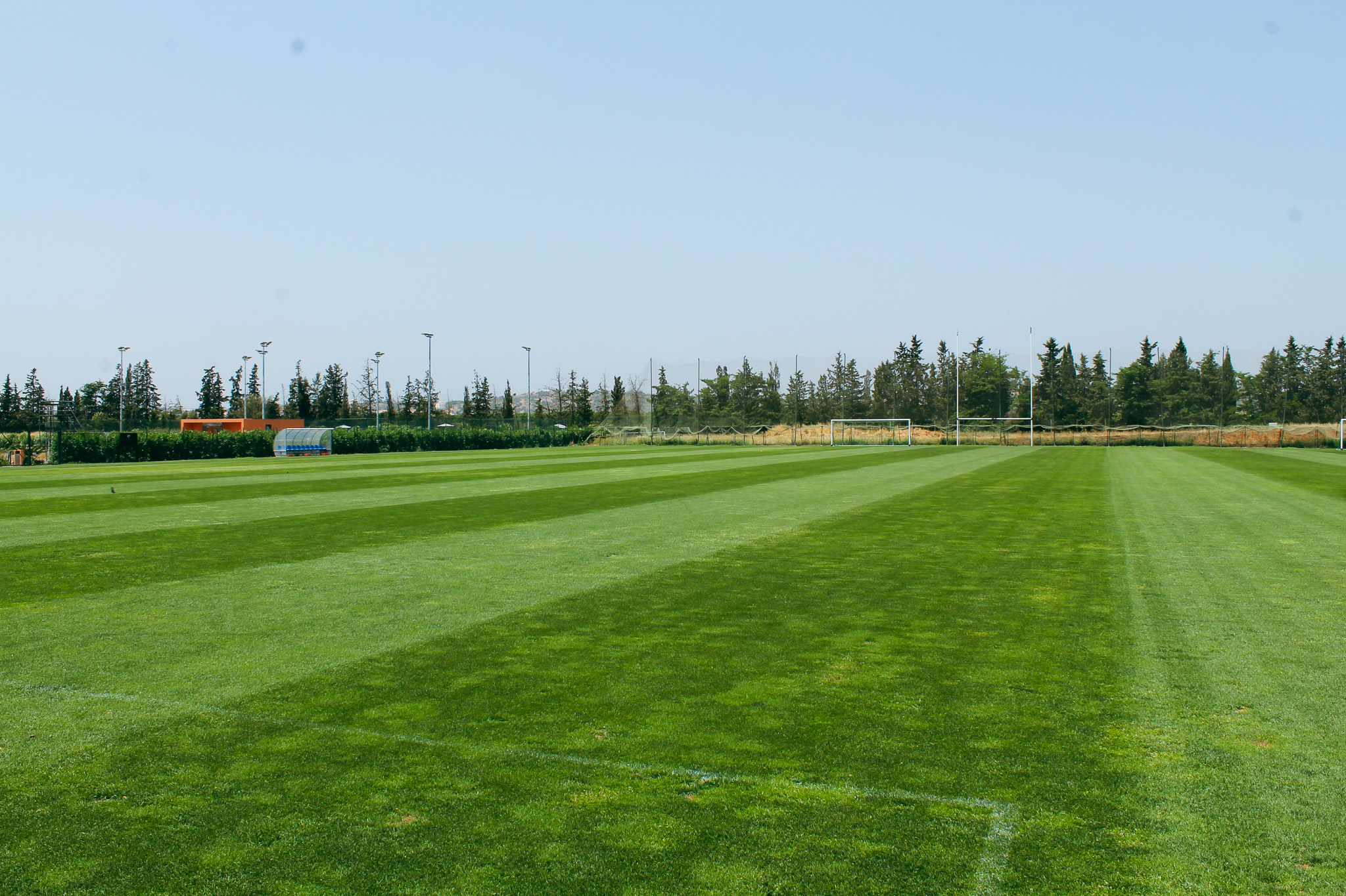 Fu&szlig;ballplatz in Portugal mit gepflegtem Rasen, umgeben von B&auml;umen.