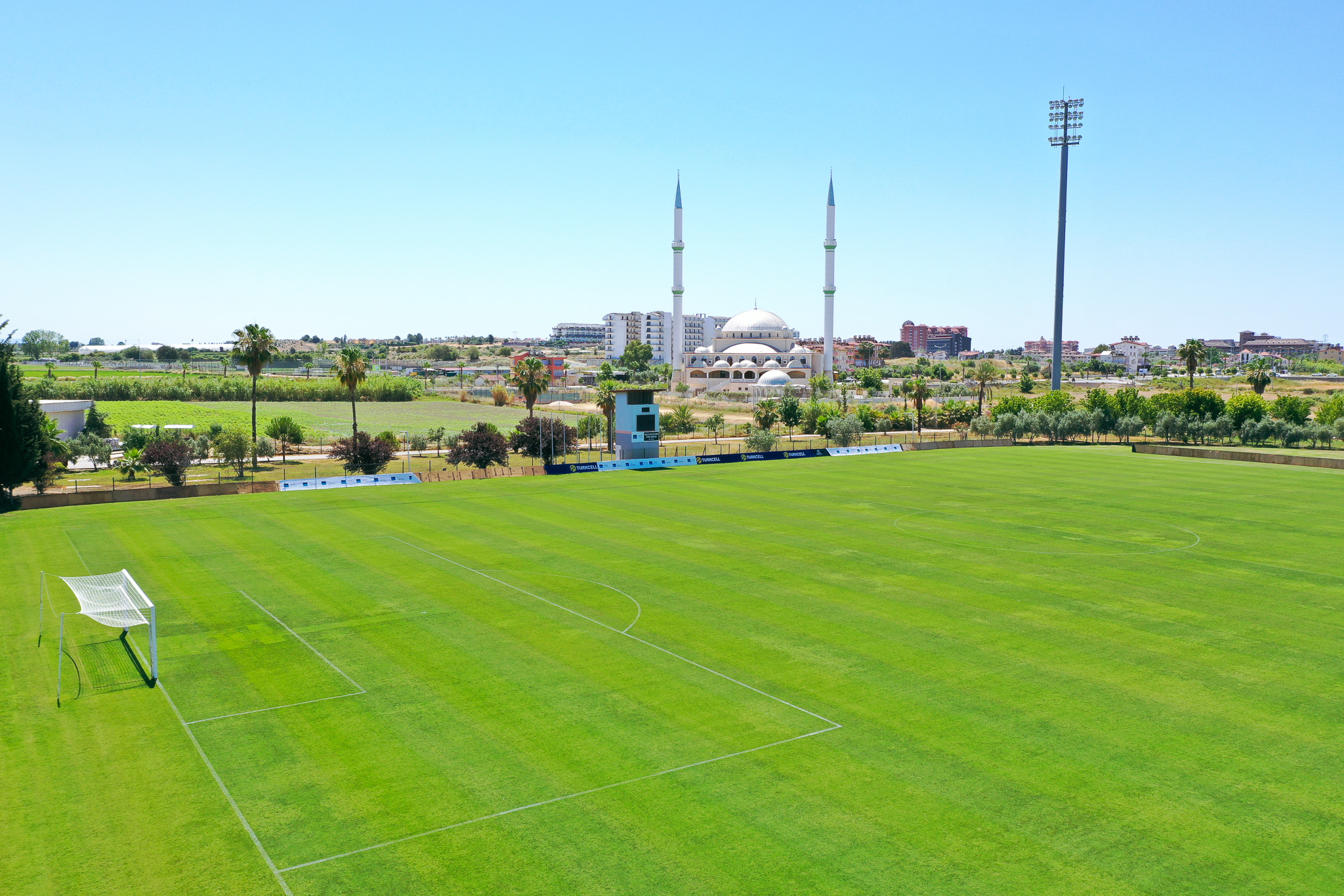  Fu&szlig;ballfeld in Side mit gr&uuml;ner Umgebung, perfektem Spielfeld und einer beeindruckenden Moschee im Hintergrund.