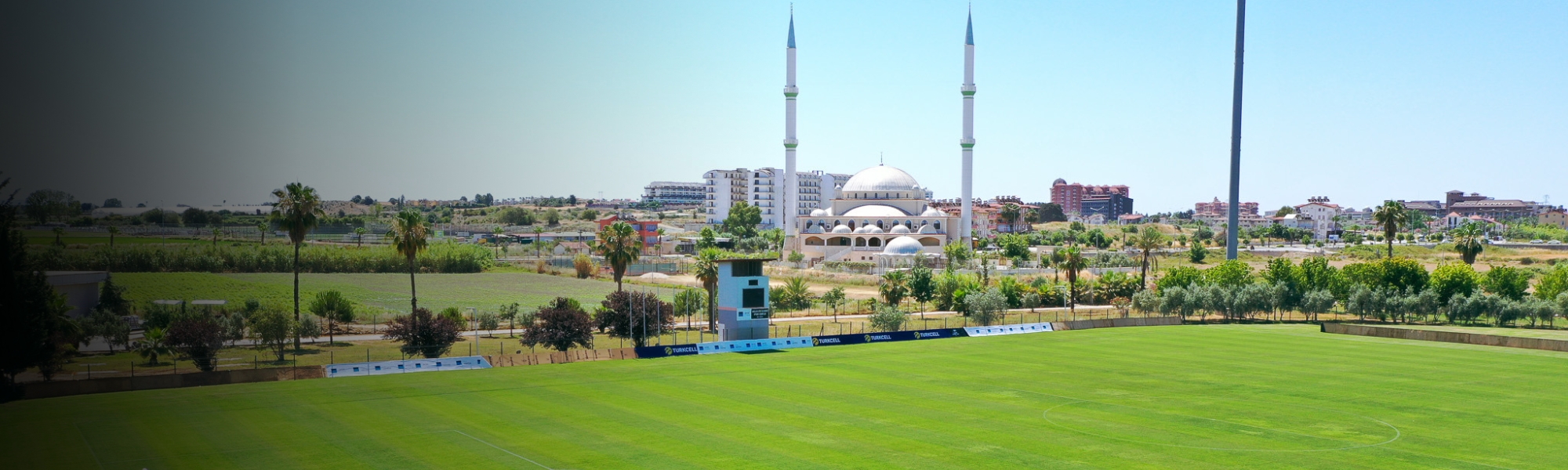  Fu&szlig;ballfeld in Side mit gr&uuml;ner Umgebung, perfektem Spielfeld und einer beeindruckenden Moschee im Hintergrund.